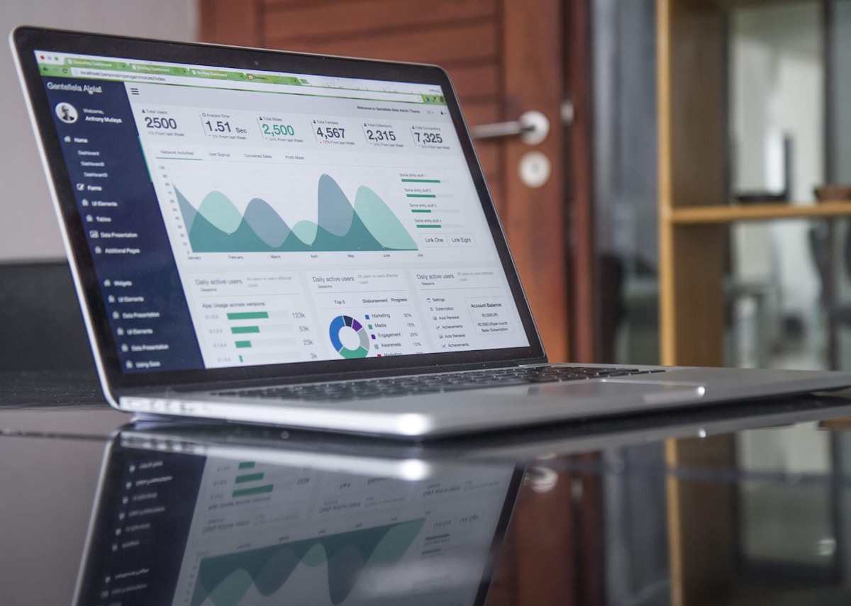 Person setting up a Google Ads campaign on a laptop with a metrics dashboard visible