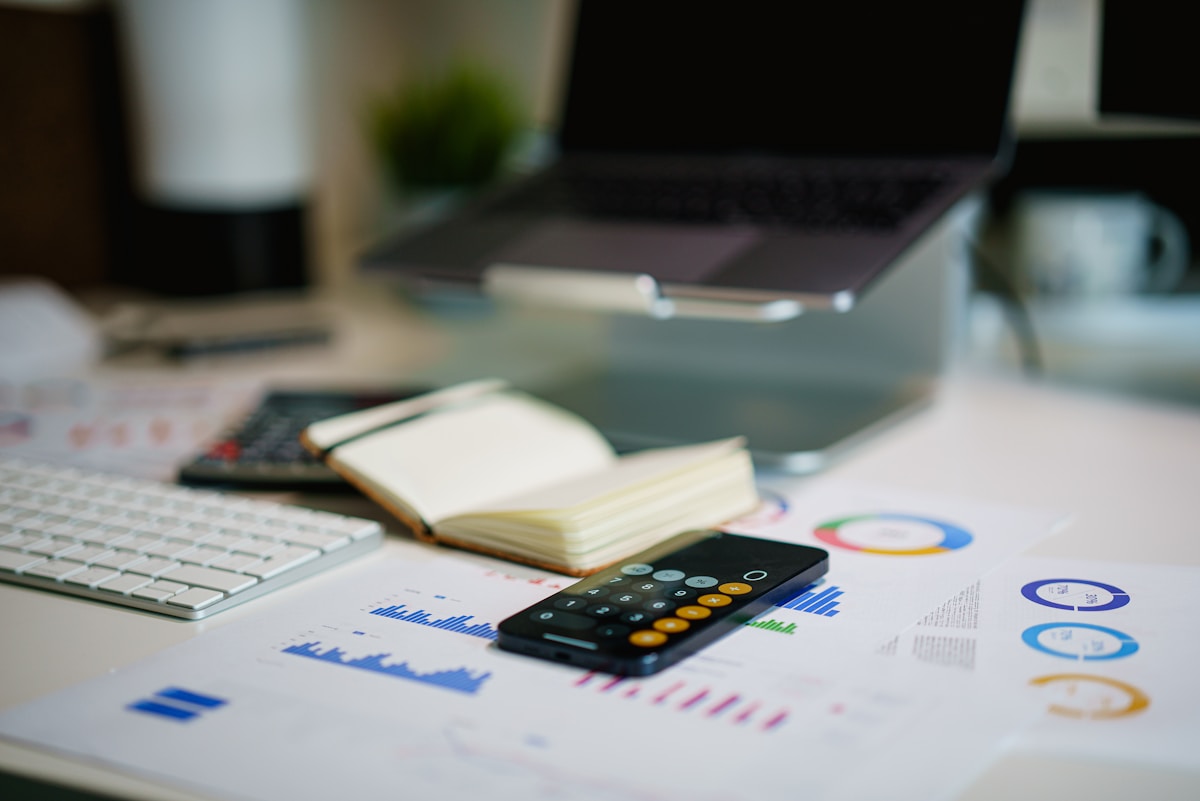 Notebook and calculator on a desk used for planning a marketing budget, with a small growth chart sketch