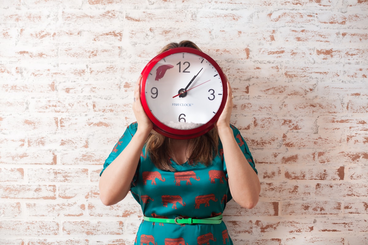 Woman covering her face with a large wall clock
