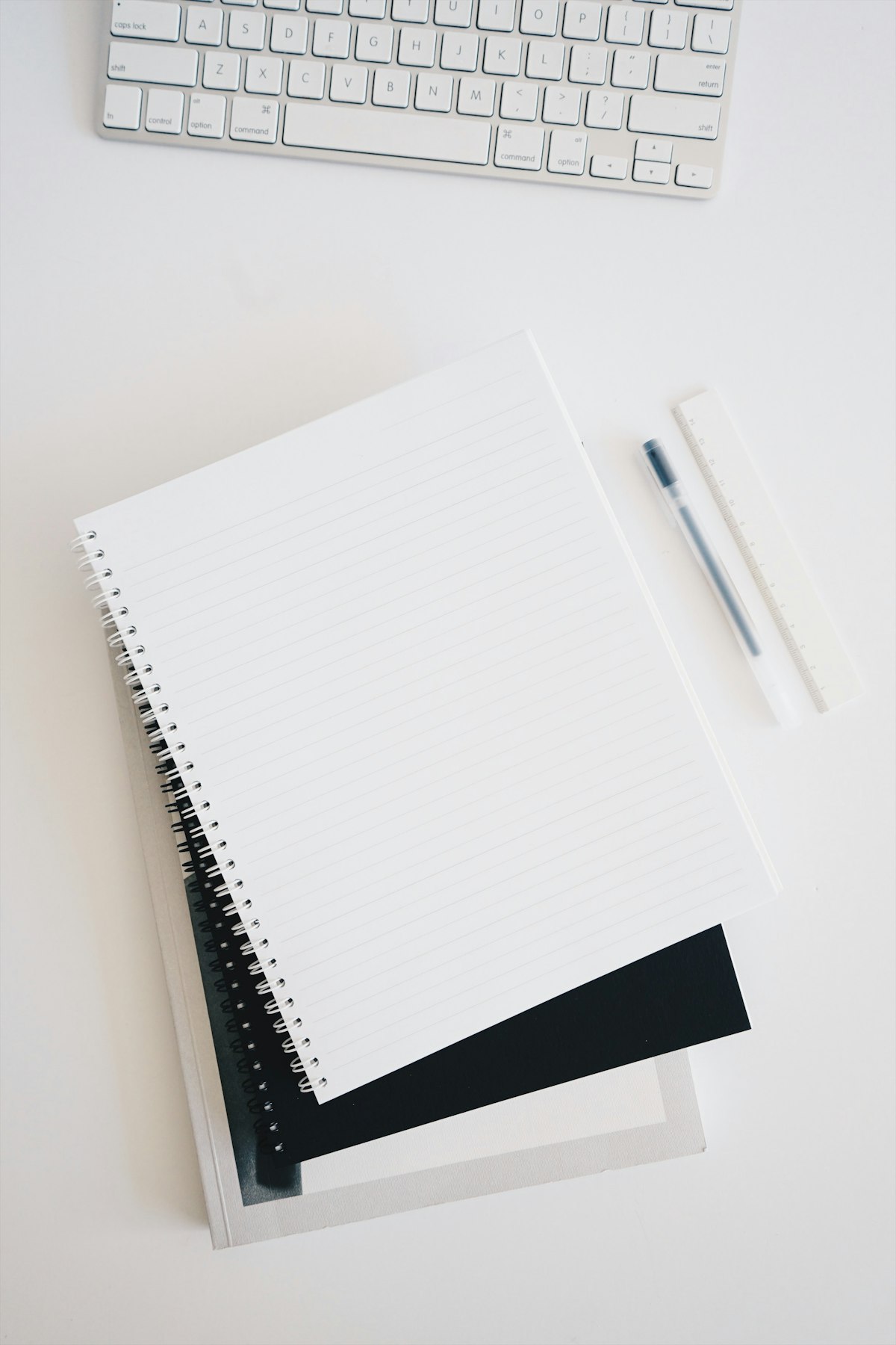Empty spiral notebook near a keyboard and pen