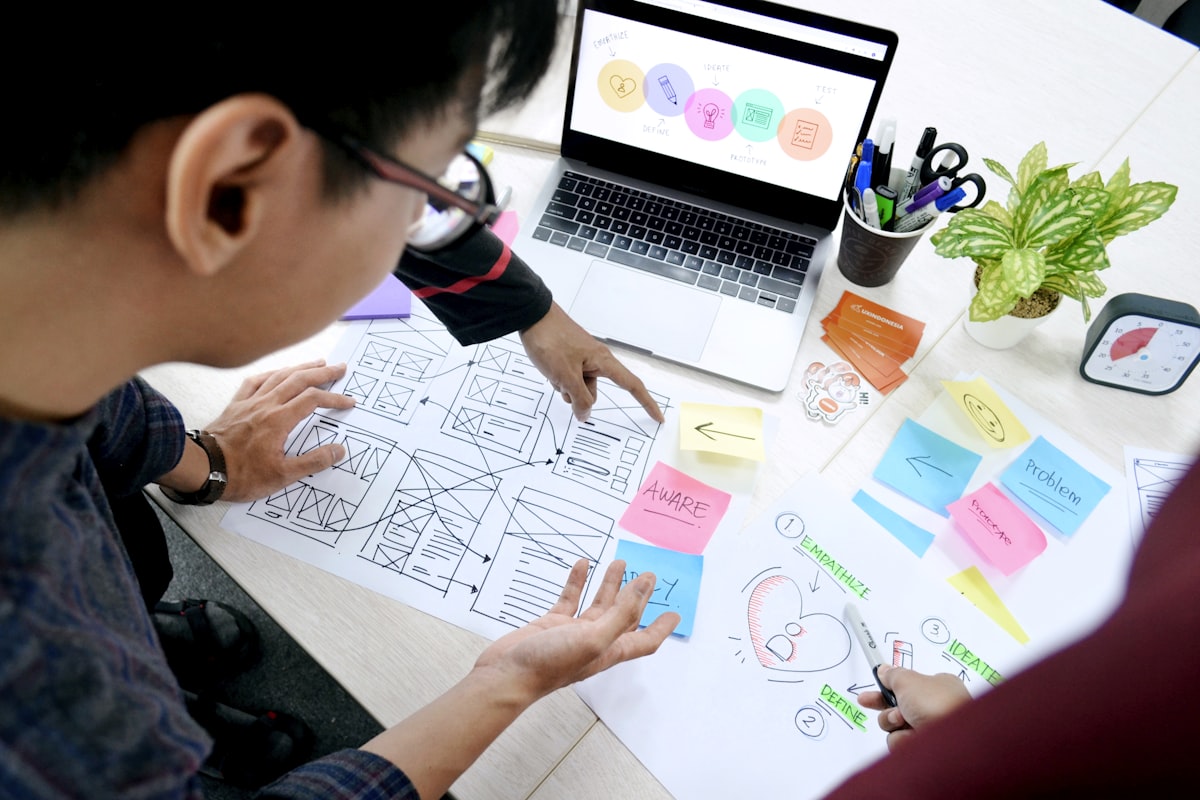 Designer working on wireframes at a desk with a laptop
