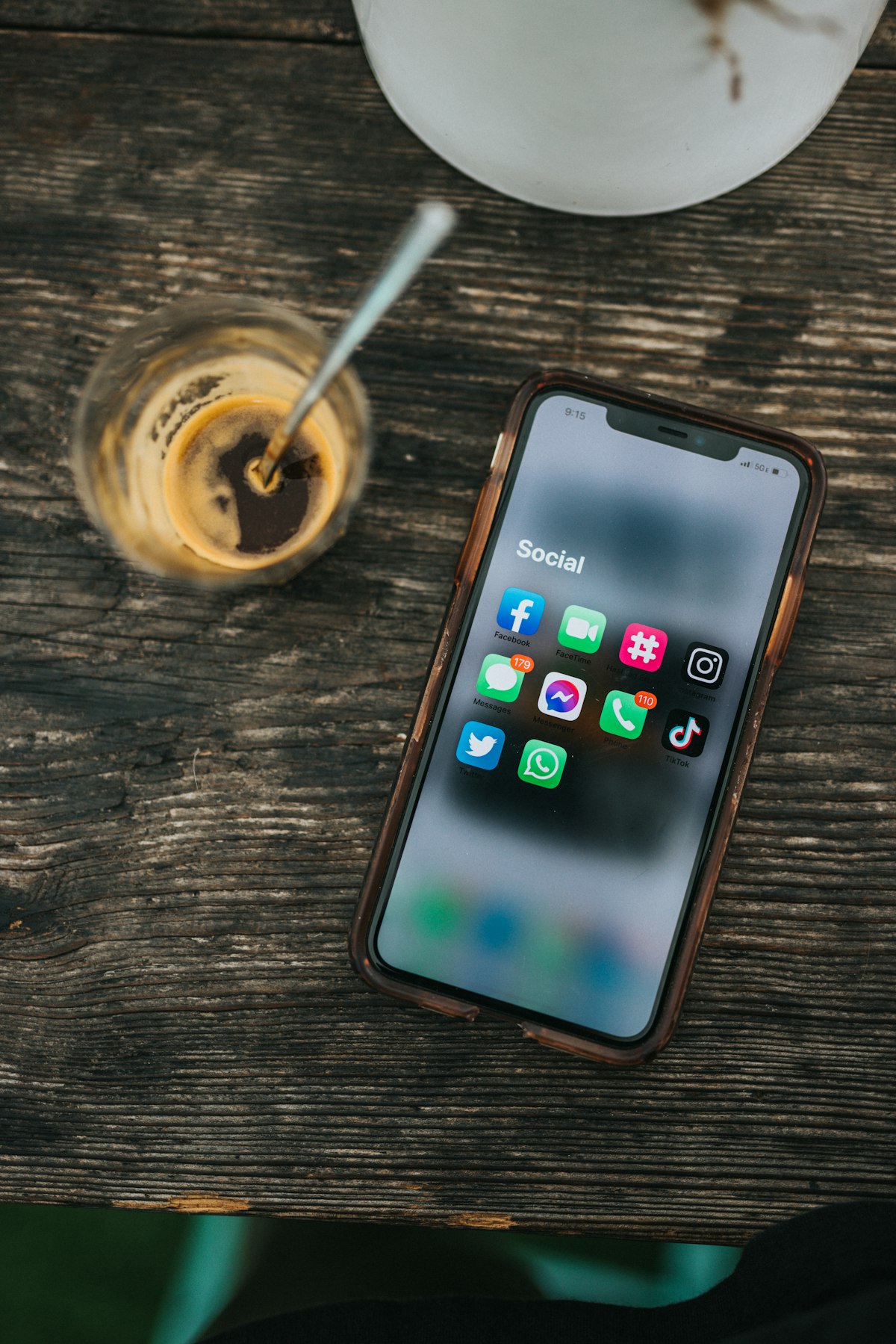 Smartphone displaying social media apps beside a coffee cup