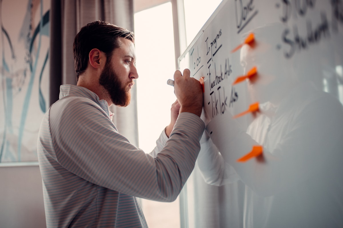A person writing on a whiteboard with markers
